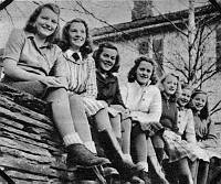 Bildet viser jentene ved Lånke Framhaldskole sittende på kirkemuren forran kommunelokalet i Lånke, året er 1946 – 47